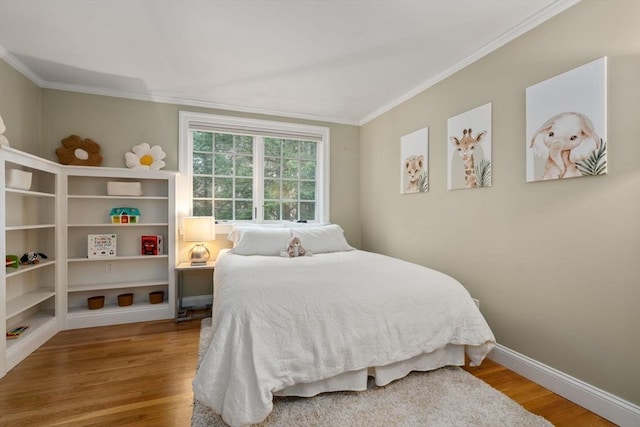 bedroom with crown molding, wood finished floors, and baseboards