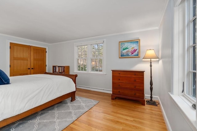 bedroom featuring a baseboard radiator, ornamental molding, and light wood-style flooring