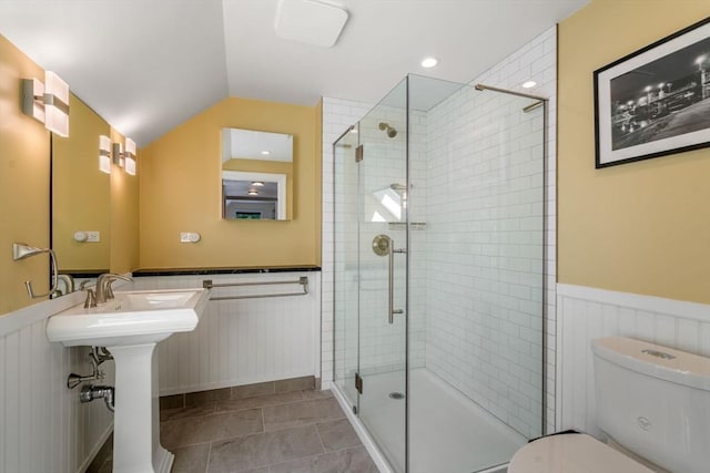 bathroom featuring wainscoting, a stall shower, toilet, and lofted ceiling