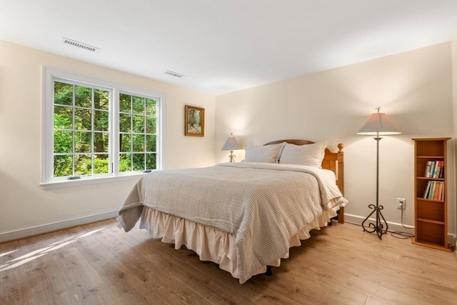 bedroom featuring visible vents, baseboards, and light wood finished floors