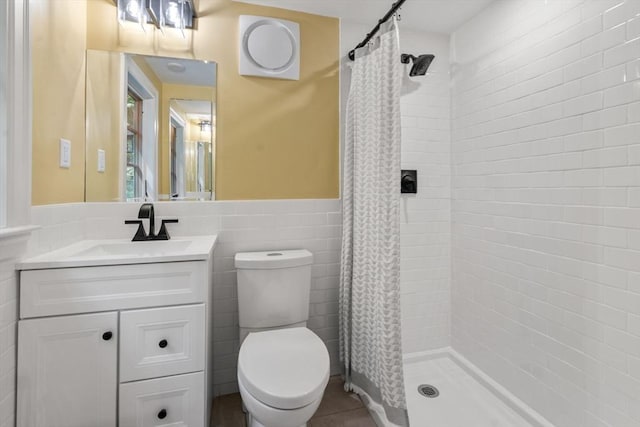 bathroom featuring vanity, a shower stall, wainscoting, tile walls, and toilet