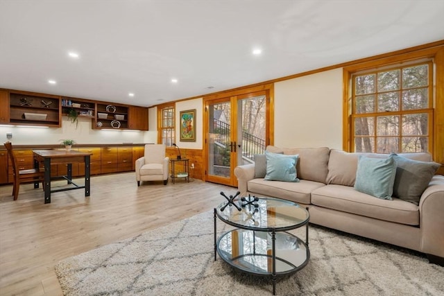 living area with crown molding, light wood-style flooring, recessed lighting, and french doors