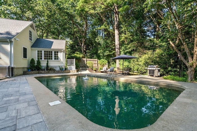 pool with area for grilling, a patio, and fence