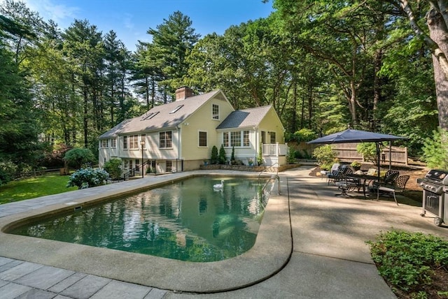 pool with outdoor dining area, fence, a grill, and a patio area