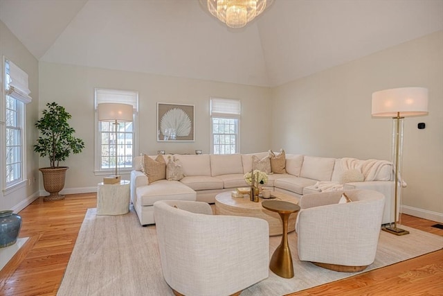 living room featuring vaulted ceiling, a healthy amount of sunlight, and light wood-type flooring