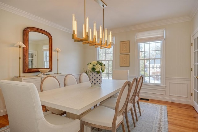 dining room featuring an inviting chandelier, ornamental molding, and light hardwood / wood-style floors