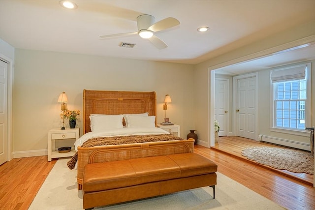 bedroom with ceiling fan, baseboard heating, and light hardwood / wood-style floors