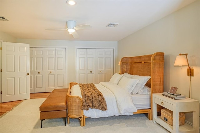 bedroom featuring multiple closets, ceiling fan, and light hardwood / wood-style flooring