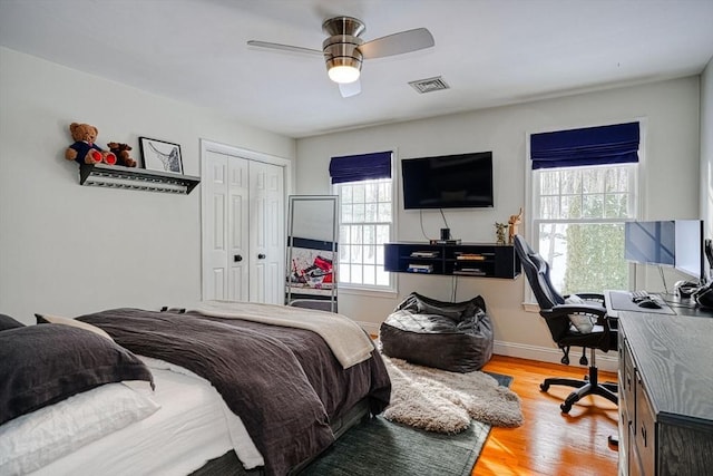 bedroom with multiple windows, ceiling fan, a closet, and light wood-type flooring