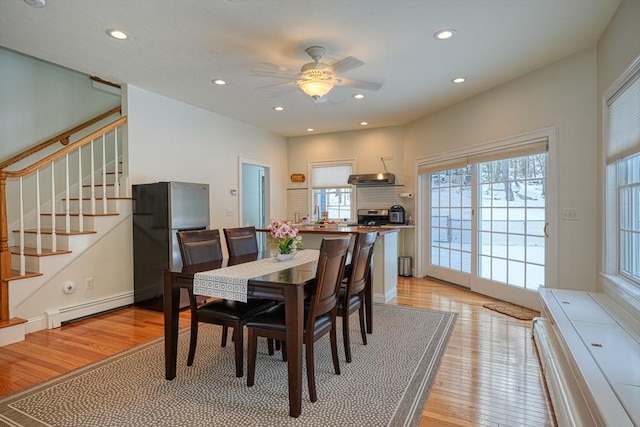 dining space featuring ceiling fan, baseboard heating, and light hardwood / wood-style flooring