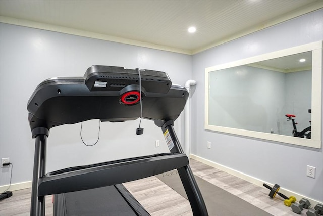 exercise room with wood-type flooring and crown molding