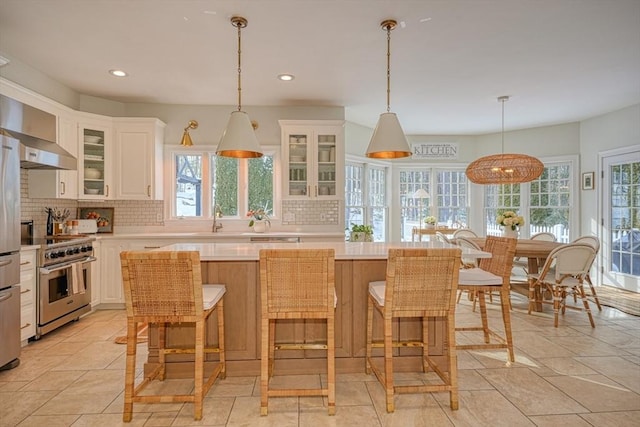 kitchen with white cabinetry, backsplash, high end stove, and a center island