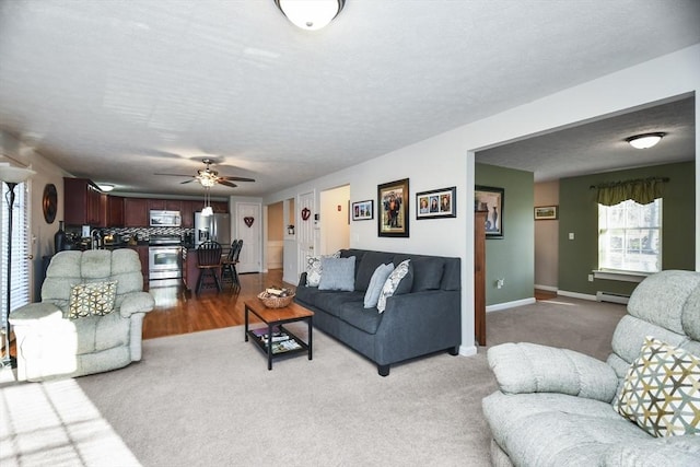 carpeted living room featuring baseboard heating, ceiling fan, and a textured ceiling