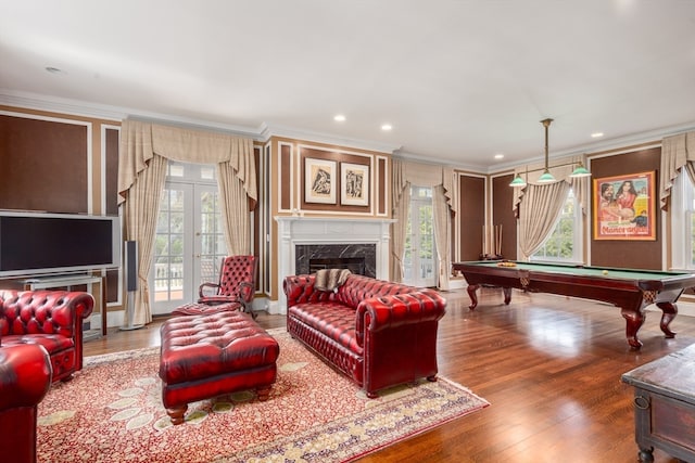 living room with a healthy amount of sunlight, hardwood / wood-style flooring, a high end fireplace, and pool table