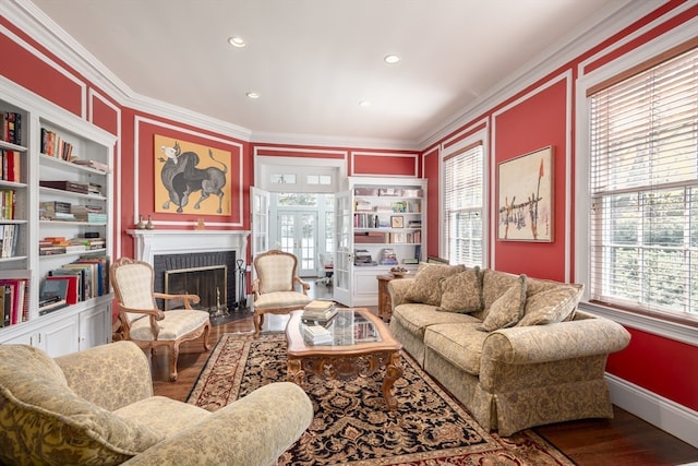 living room featuring built in features, wood-type flooring, a brick fireplace, and a wealth of natural light