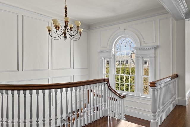 staircase featuring dark hardwood / wood-style floors, an inviting chandelier, and ornamental molding