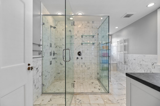 bathroom featuring vanity, an enclosed shower, tile flooring, and tile walls