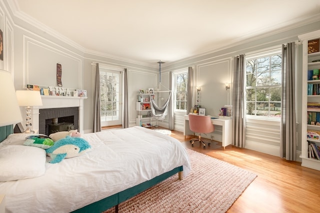 bedroom featuring ornamental molding, a brick fireplace, and light wood-type flooring