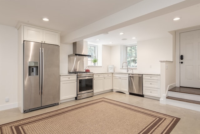 kitchen with wall chimney exhaust hood, stainless steel appliances, white cabinetry, and sink