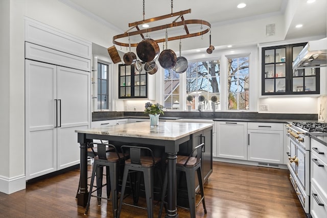 kitchen featuring a kitchen bar, white cabinets, dark stone countertops, dark hardwood / wood-style flooring, and a center island