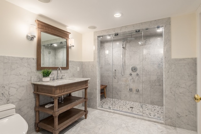 bathroom with a shower with door, tile floors, vanity, tile walls, and toilet