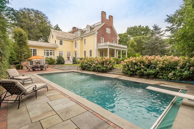 view of pool with a diving board and a patio