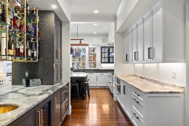 bar featuring light stone counters, white cabinetry, crown molding, stainless steel oven, and dark hardwood / wood-style floors