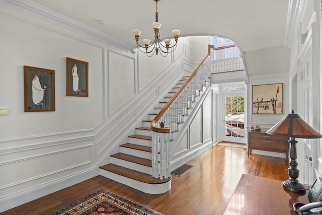 staircase featuring ornamental molding, wood-type flooring, and a chandelier