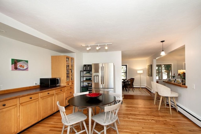 kitchen featuring light hardwood / wood-style floors, a baseboard heating unit, hanging light fixtures, and appliances with stainless steel finishes