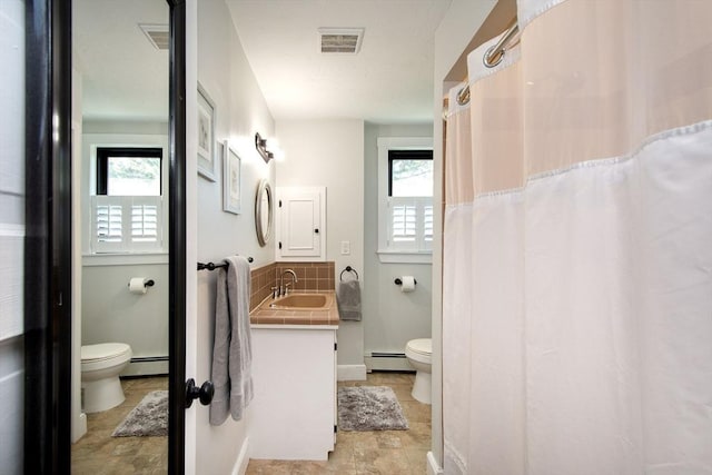 bathroom featuring a baseboard radiator, toilet, plenty of natural light, and tasteful backsplash