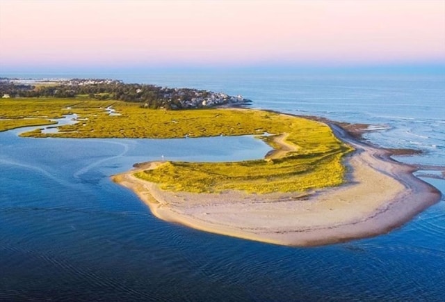 aerial view at dusk featuring a water view and a view of the beach