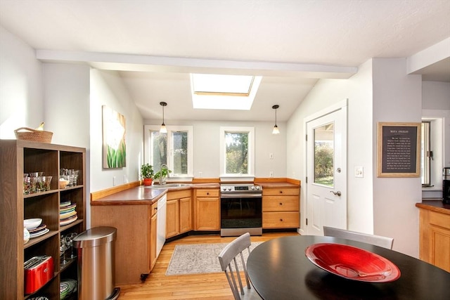 kitchen featuring sink, decorative light fixtures, stainless steel range with electric cooktop, and vaulted ceiling with skylight