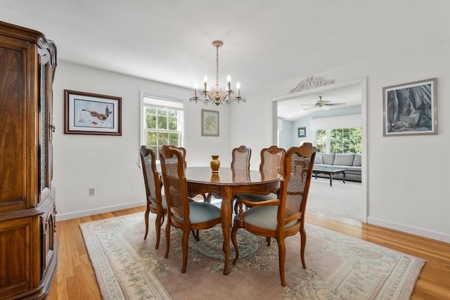 dining area featuring a chandelier, light wood-style flooring, baseboards, and a ceiling fan