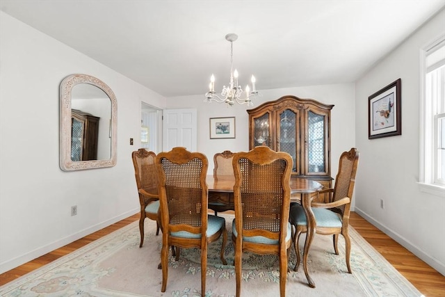 dining room with a chandelier, light wood-style floors, and baseboards