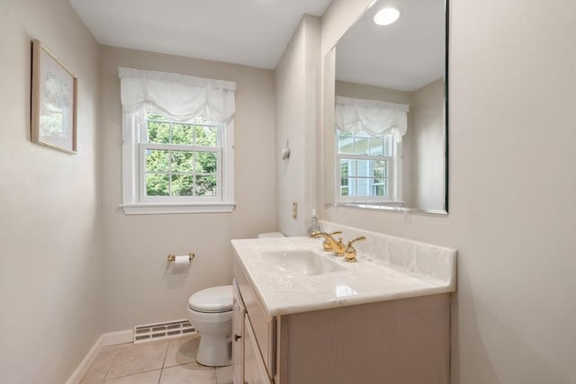 half bathroom featuring plenty of natural light, toilet, vanity, and baseboards