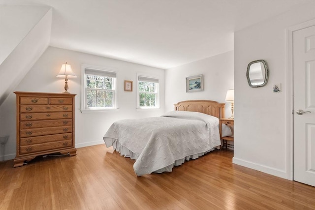 bedroom with wood finished floors, baseboards, and vaulted ceiling