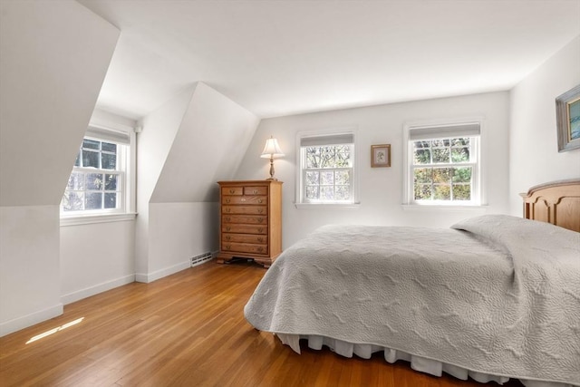 bedroom featuring wood finished floors, baseboards, and lofted ceiling