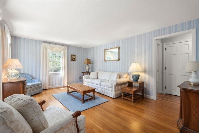 living room featuring wallpapered walls, light wood-type flooring, and baseboards
