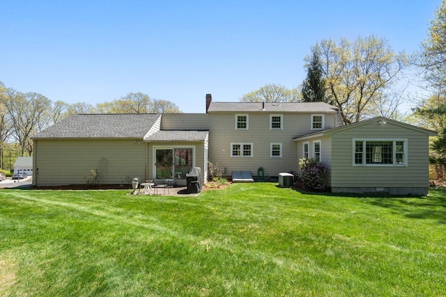 back of house featuring a lawn, a chimney, and central AC unit