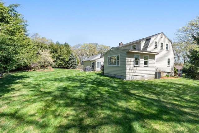 rear view of house featuring a yard, a chimney, and central air condition unit