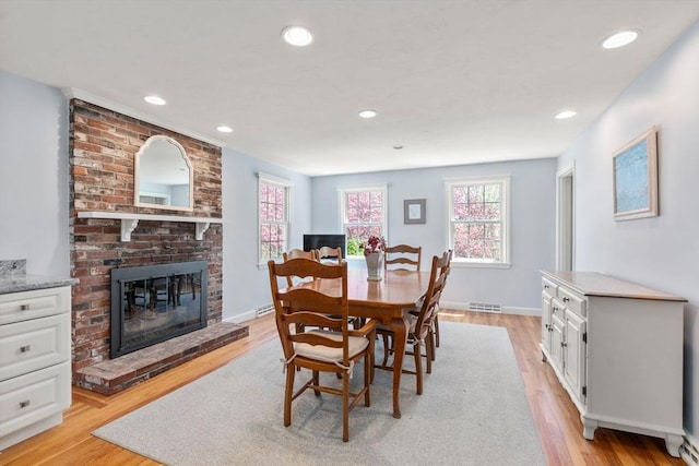 dining space with a brick fireplace, light wood finished floors, recessed lighting, and baseboards