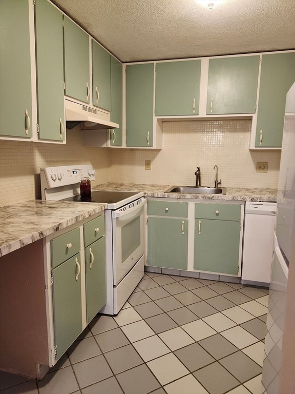 kitchen featuring sink, a textured ceiling, light tile patterned floors, green cabinetry, and white appliances