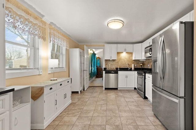 kitchen featuring sink, light tile patterned floors, white cabinetry, stainless steel appliances, and tasteful backsplash