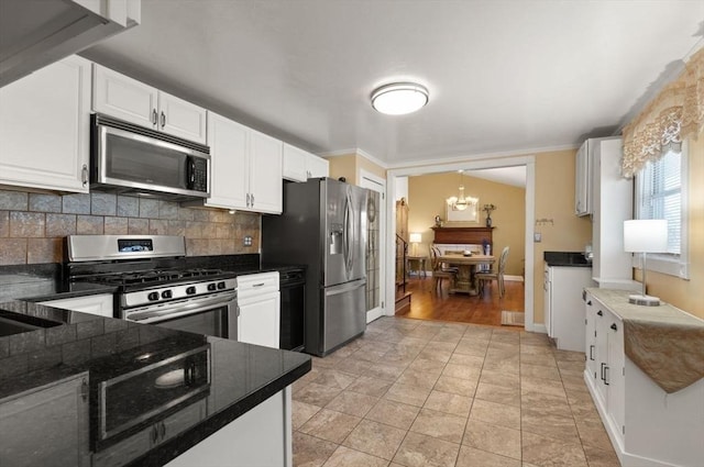 kitchen featuring white cabinetry, decorative light fixtures, dark stone counters, stainless steel appliances, and backsplash