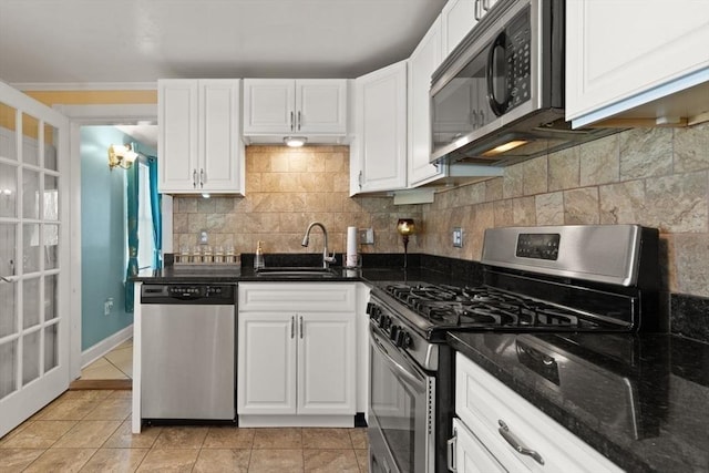 kitchen with white cabinetry, appliances with stainless steel finishes, backsplash, and dark stone counters