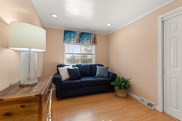 living room with ornamental molding and light hardwood / wood-style flooring