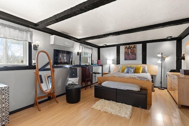 bedroom with beam ceiling, light hardwood / wood-style floors, and a wall unit AC