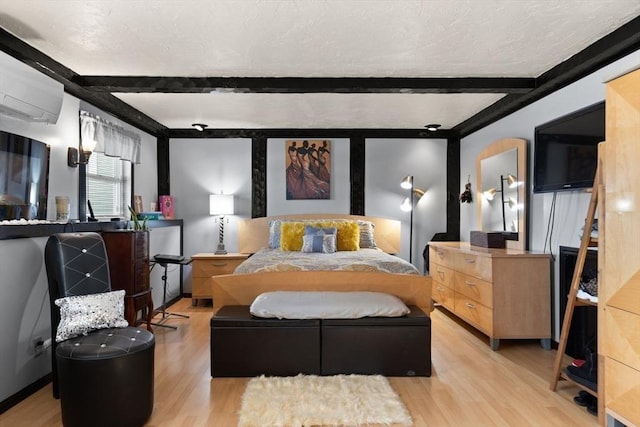 bedroom with a textured ceiling, light hardwood / wood-style flooring, an AC wall unit, and beamed ceiling