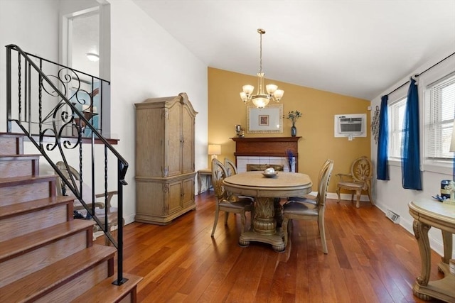dining space featuring hardwood / wood-style flooring, a wall mounted AC, vaulted ceiling, and a notable chandelier