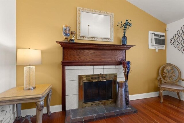 sitting room featuring a tile fireplace, lofted ceiling, dark hardwood / wood-style floors, and a wall mounted AC